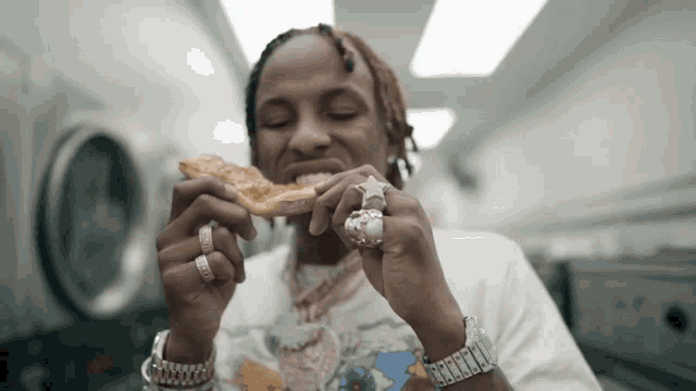 a man with rings on his fingers is eating a pizza