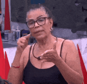 a woman wearing glasses and a black tank top is making a funny face .