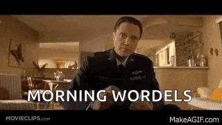 a man in a suit and tie is sitting at a table in a living room with the words `` morning wordels '' .
