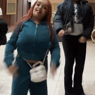 a woman in a blue jacket is dancing with a man in a black jacket in the background