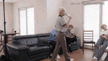 a man singing into a microphone in a living room with the words marry me in the corner