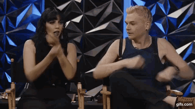 a man and a woman are sitting next to each other in chairs and talking .