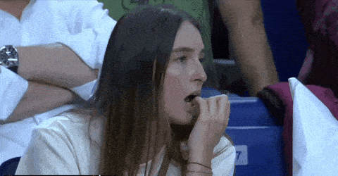 a woman bites her nails while watching a game in a stadium with the number 7 on the bleachers