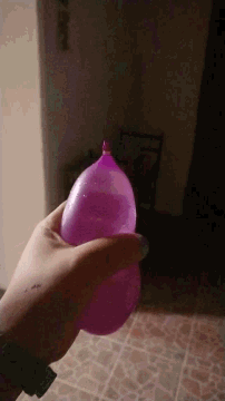 a person is holding a pink water balloon