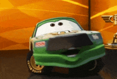 a green toy car from the movie cars is standing next to a gold trophy .