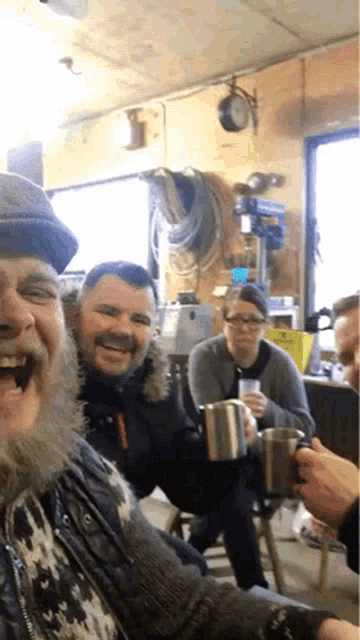 a man with a beard is laughing while holding a cup of coffee