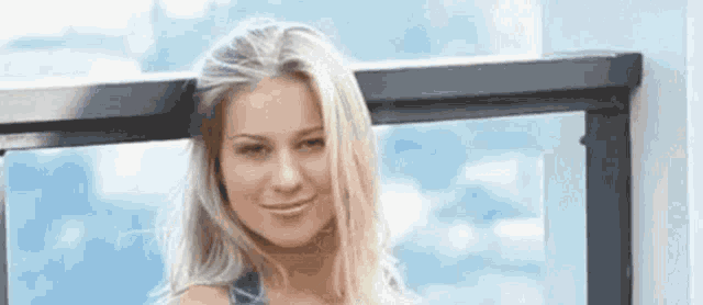 a woman is leaning against a railing on a balcony and smiling .