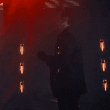 a man in a suit is standing in a dark room