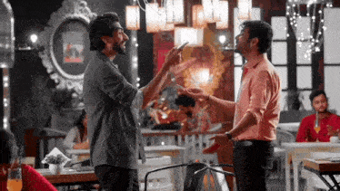 two men are standing next to each other in a restaurant and talking to each other .