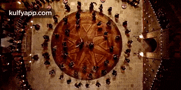 a group of people are dancing in a circle on a wooden floor .
