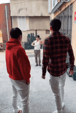 a man in a red hoodie stands next to two other men in plaid shirts
