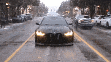 a black bmw is driving down a wet street