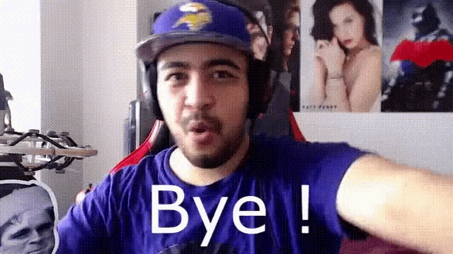 a man wearing headphones and a baseball cap is saying bye .