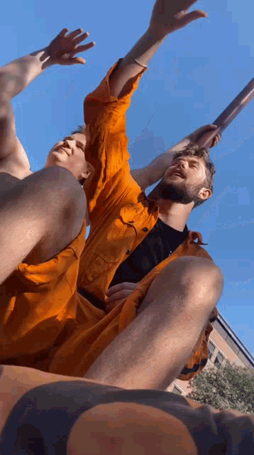 a man with a tattoo on his leg is holding another man 's arm in the air