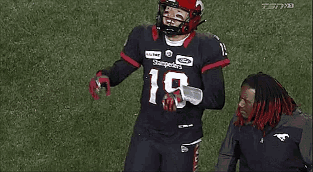 a football player wearing a black jersey with the number 19 on it is standing on a field .