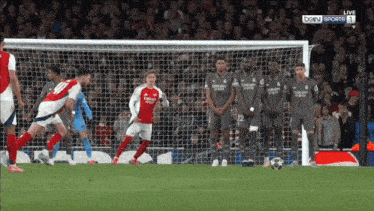 a group of soccer players wearing emirates jerseys stand in front of a soccer goal