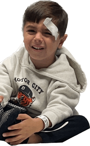 a young boy with a bandage on his forehead is wearing a motor city hoodie