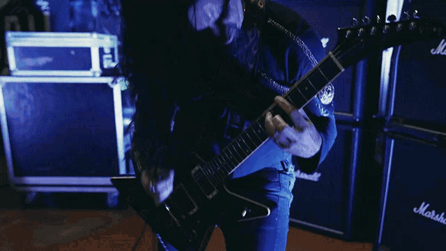 a man playing a guitar in front of marshall amps
