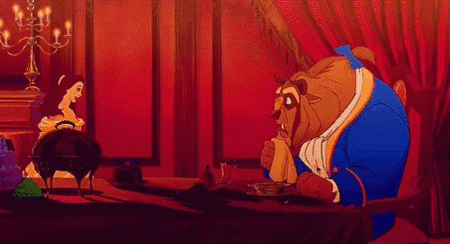 a woman in a dress is sitting at a table with a beast .