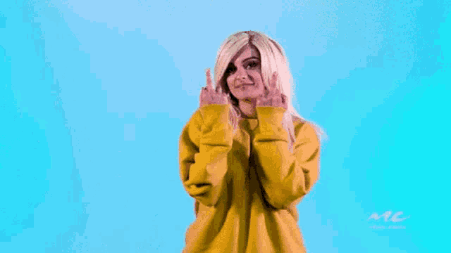 a woman wearing a yellow sweatshirt is making a funny face .