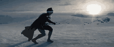 a man in a cape is walking on a snow covered field .