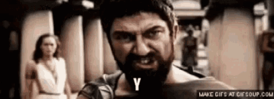 a man with a beard is standing in front of a woman and y is written on his face .
