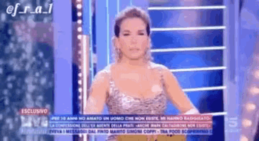 a woman in a silver dress is standing in front of a blue screen .