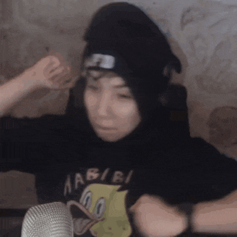 a man wearing a black hoodie and a headband is sitting in front of a microphone .