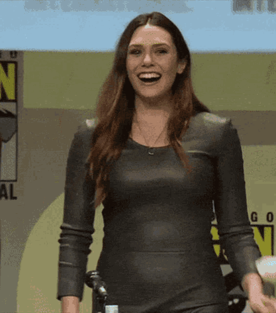 a woman in a leather dress is smiling in front of a sign that says n on it