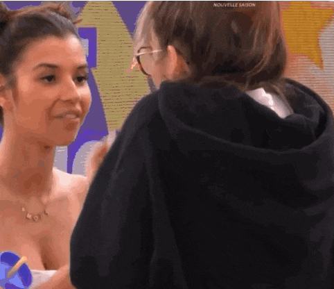 a woman in a black hoodie talks to another woman in a white dress