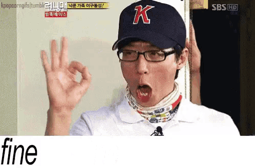 a man wearing glasses and a k hat giving an ok sign