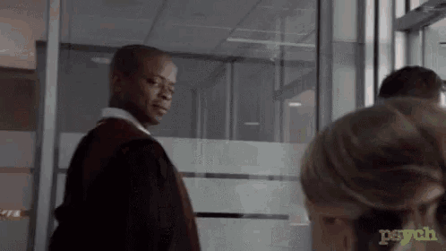 a man in a suit is standing next to a woman in a room with a sign that says psych on it .