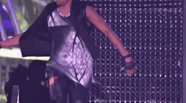 a man is dancing on a stage in front of a purple wall with lights .