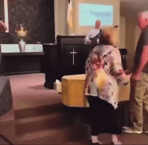 a woman in a floral shirt is standing in front of a podium with a cross on it