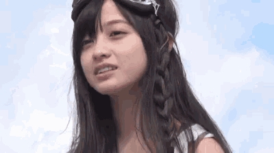 a close up of a young woman wearing goggles and a braided headband .
