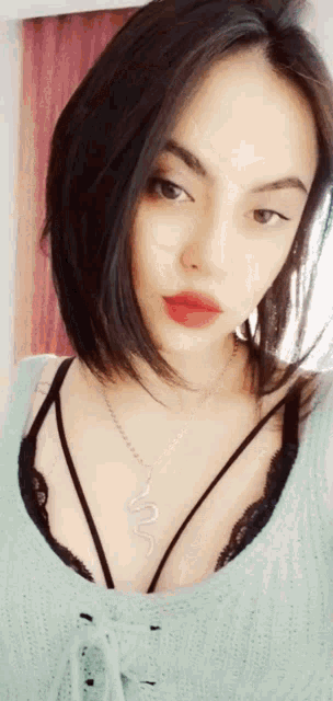 a woman wearing a necklace with a snake on it is taking a selfie