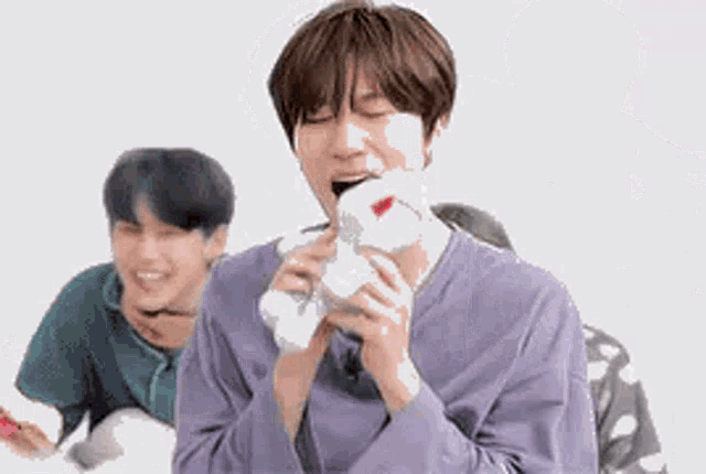 a man in a purple shirt is holding a stuffed animal .