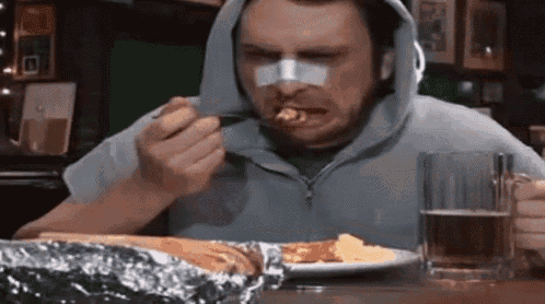a man with a bandage on his nose is sitting at a table eating food .