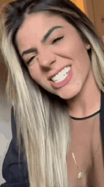 a woman with long blonde hair is smiling and wearing a black shirt