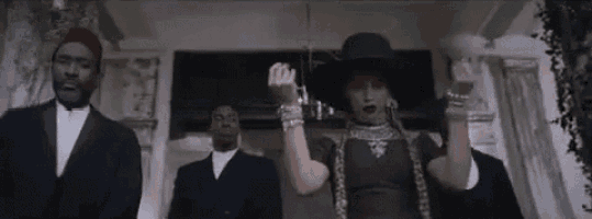 a woman in a black hat is standing in front of a group of men .
