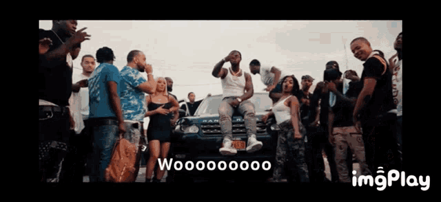 a man is sitting on the hood of a range rover surrounded by a group of people