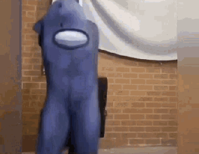 a person in an among us costume is dancing in front of a brick wall .