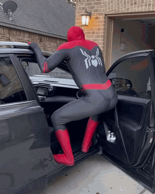 a person in a spiderman costume climbs into a car
