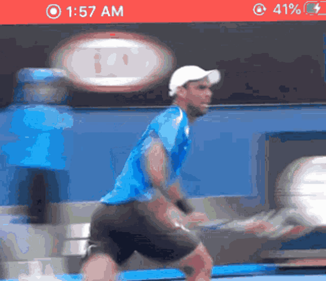 a man in a blue shirt and white hat is playing tennis