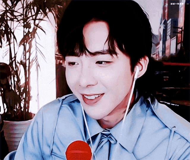 a man wearing a blue shirt and ear buds looks at the camera