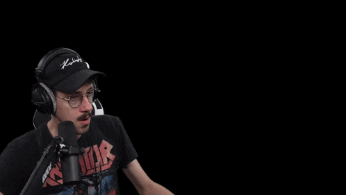a man wearing headphones and a hat is sitting in front of a microphone with a crown on the back of the chair
