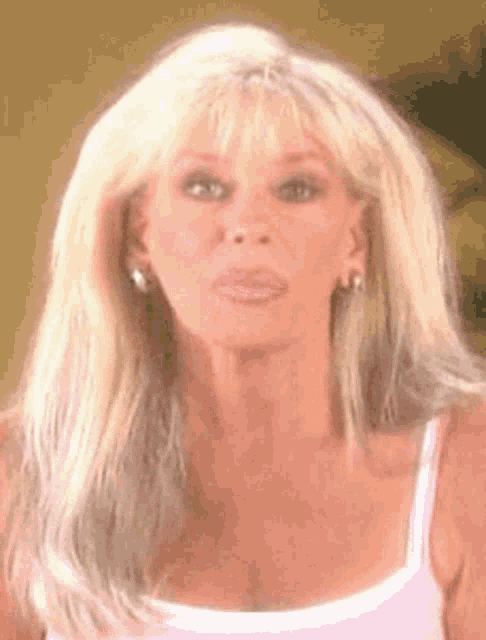 a close up of a woman 's face with blonde hair and earrings .