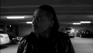 a man is standing in a parking garage with cars parked in it .