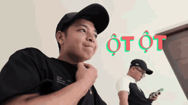 a man wearing a black hat stands next to another man wearing a white shirt with the word ot ot on it