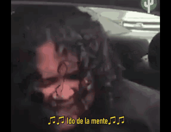 a woman with curly hair is sitting in the back seat of a car and smiling at the camera .